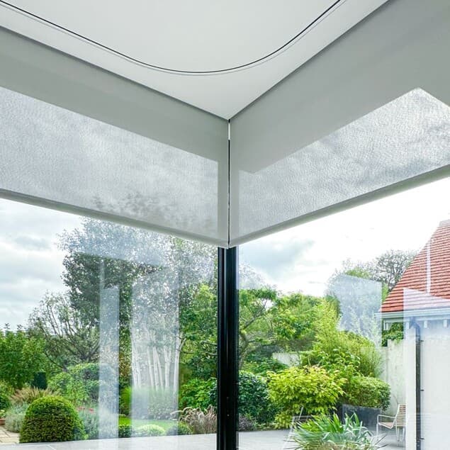 Roller shades concealed in a recessed ceiling pocket at a glass corner window